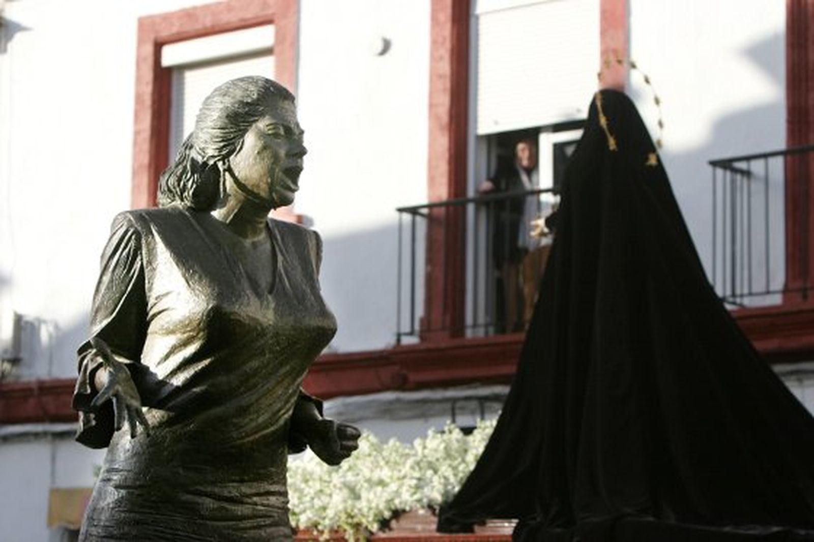 Las andas de Nuestra Señora de Amor y Sacrificio pasan ante la efigie que rinde homenaje a la Paquera de Jerez en el barrio de la Plazuela, uno de las escuelas flamencas del cante gitano de Jerez.

Foto: Vanesa Lobo