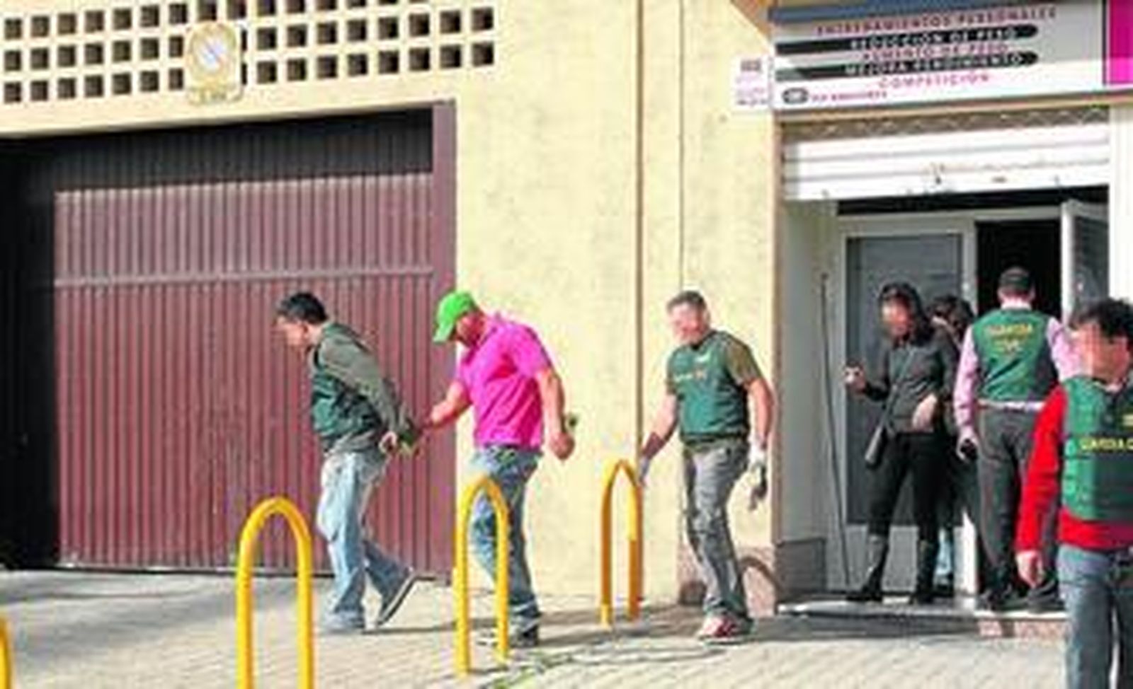 Un agente de la Guardia Civil acompaña al detenido, cabizbajo, tras un registro en uno de los comercios registrados ayer en Algeciras.