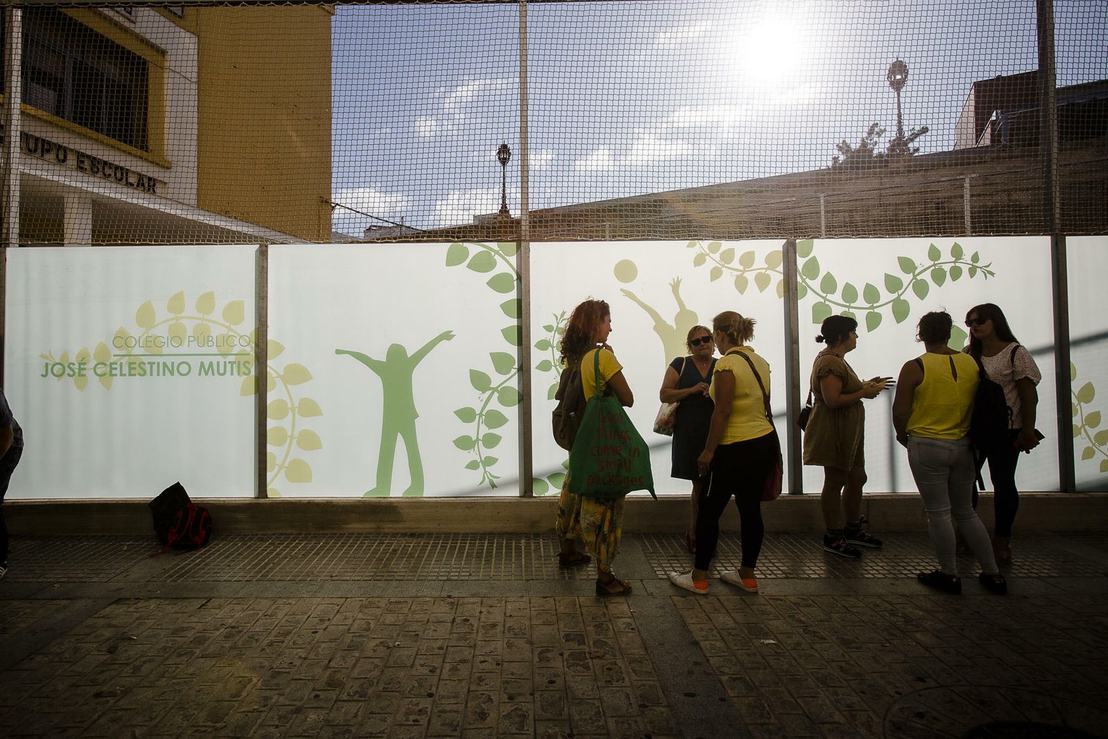 Madres de alumnos con camisetas amarillas como protesta junto al muro del patio.