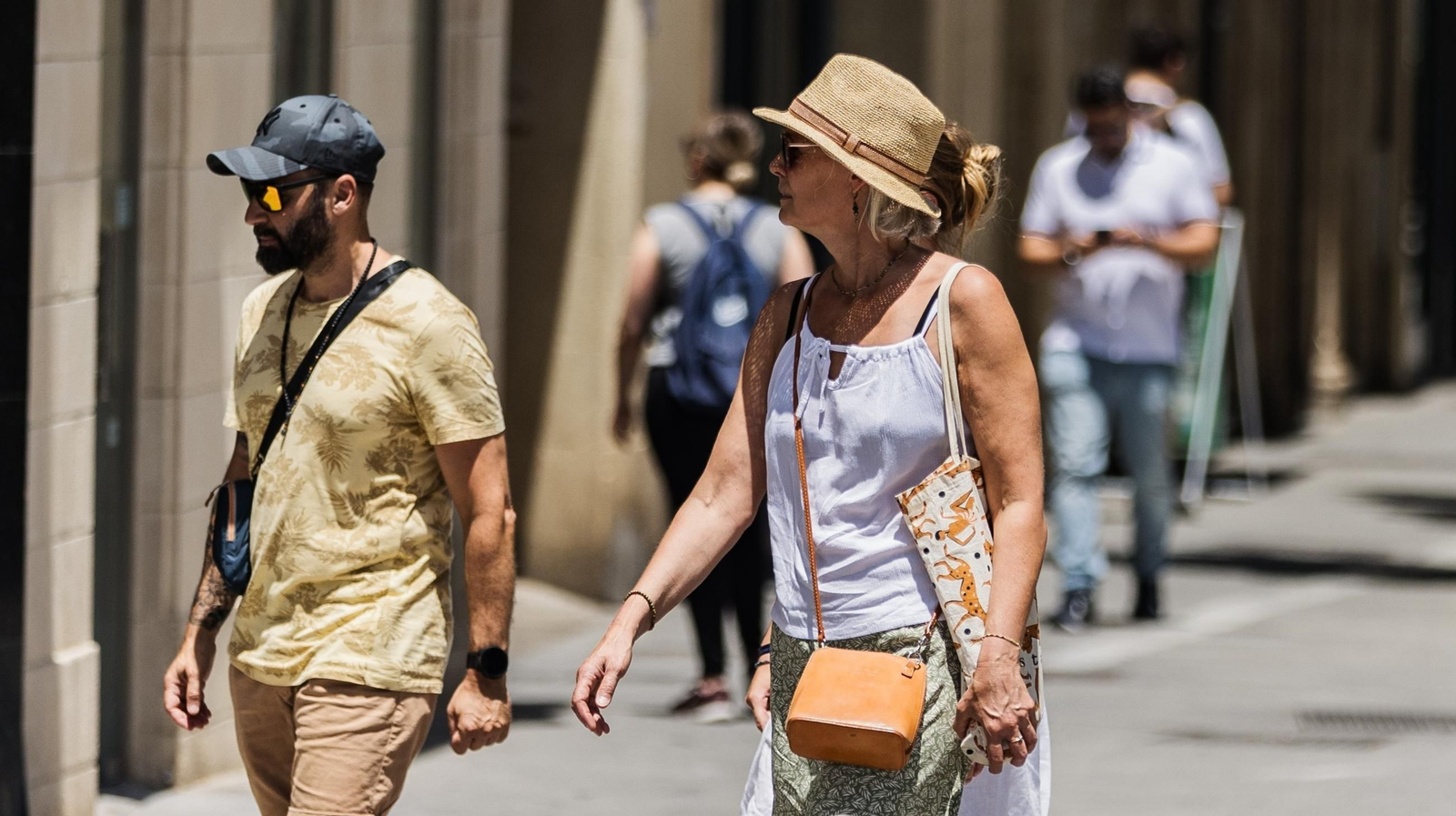Dos turistas pasean por el centro de Jerez con gafas de sol, gorra y sombrero para protegerse del sol Dos turistas pasean por el centro de Jerez con gafas de sol, gorra y sombrero para protegerse del sol