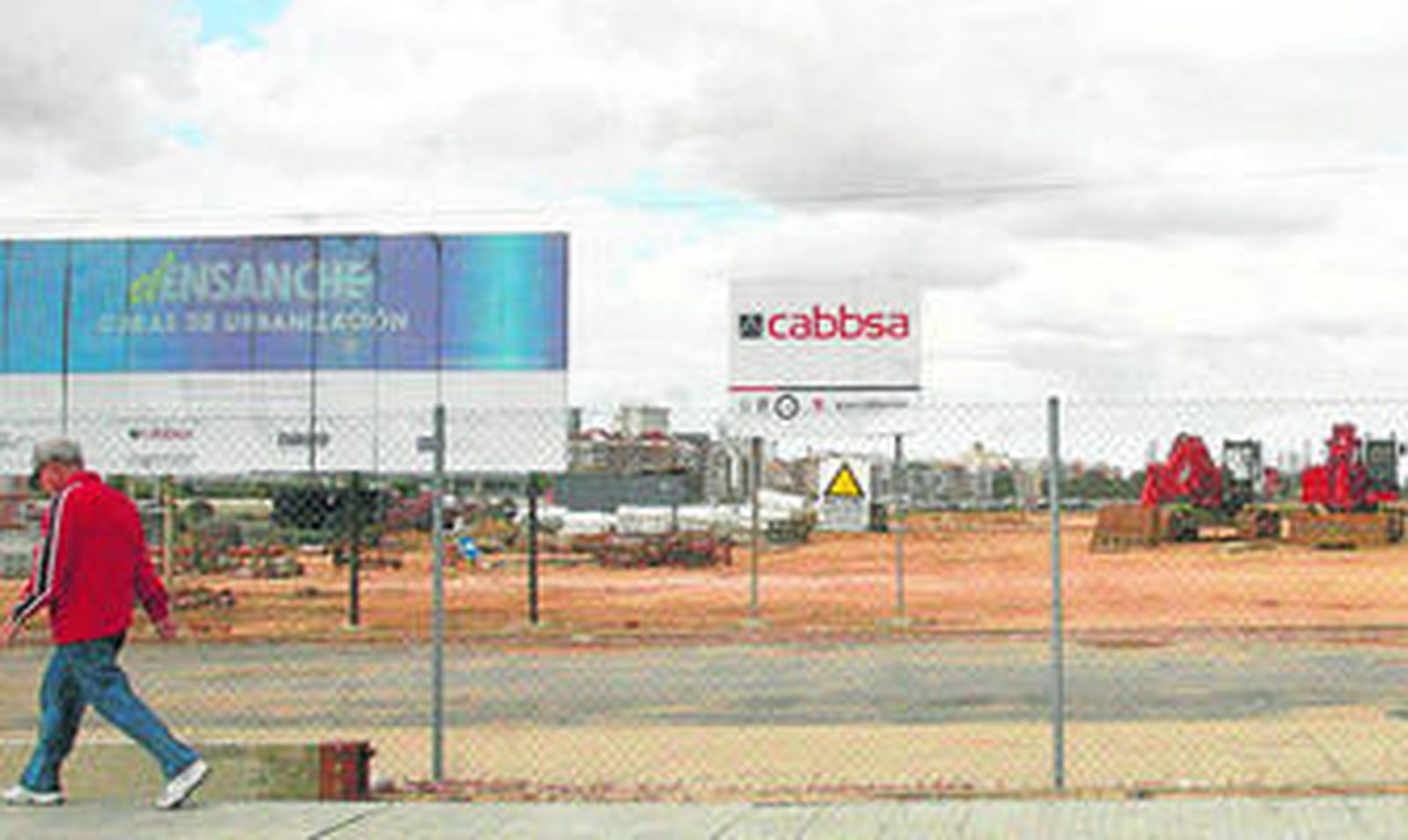 Un hombre camina delante de los terrenos del Ensanche, en los que permanecen las máquinas paradas.