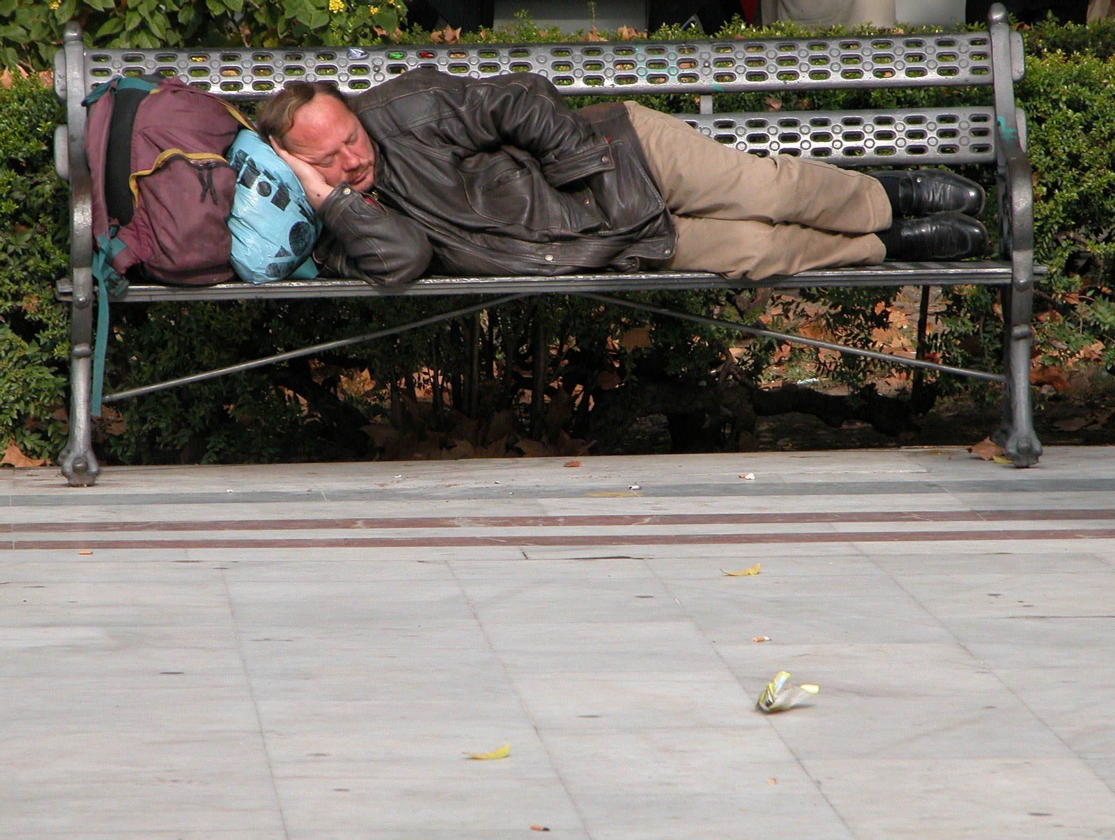 Una persona sin hogar duerme en un banco en la Plaza Nueva.