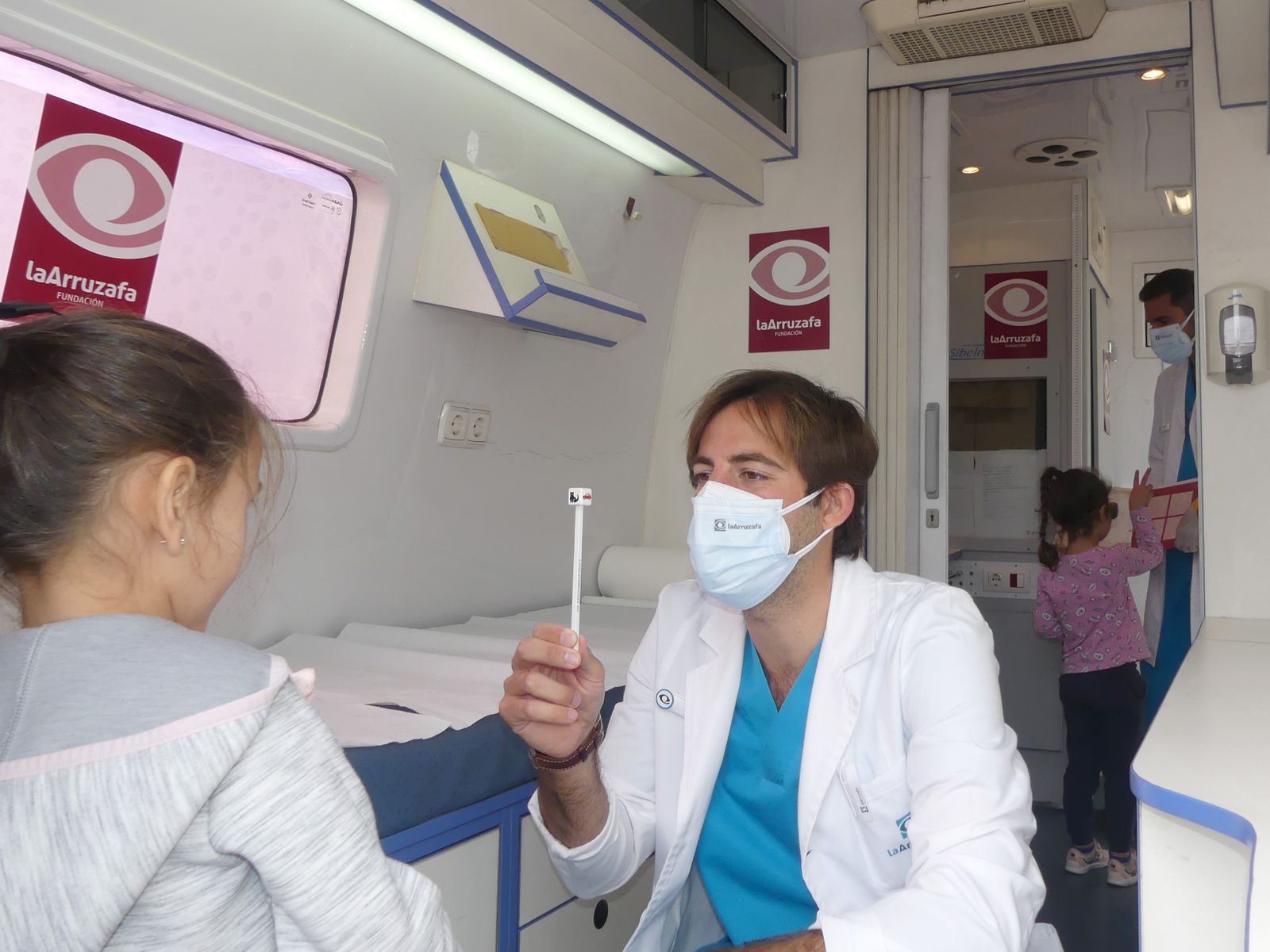 Profesional sanitario realiza una prueba de oftalmología a una niña.