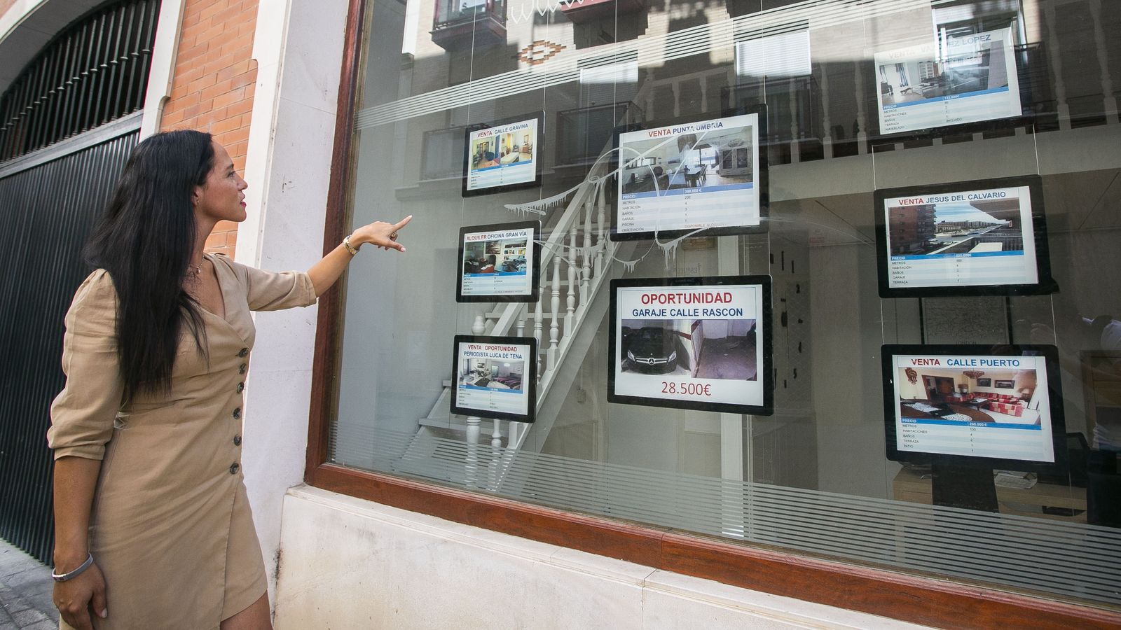 Una mujer mira anuncios de viviendas de una inmobiliaria.