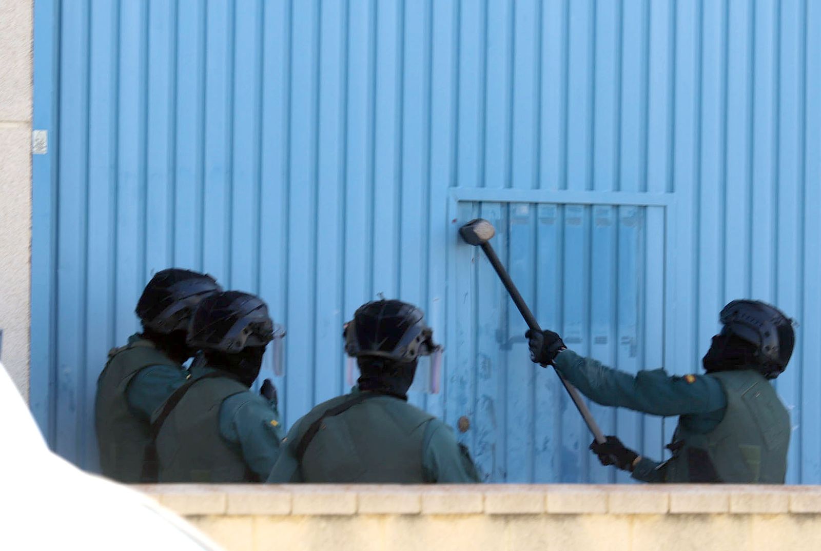 Agentes de la Guardia Civil golpean una puerta durante un registro.