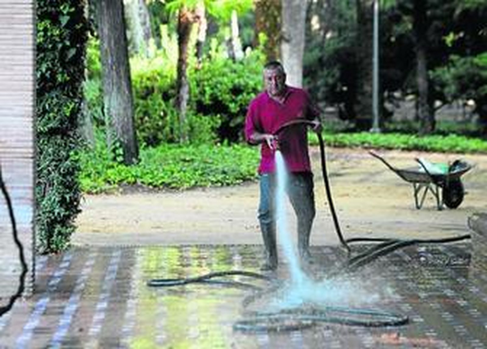 Un operario de Parques y Jardines realiza labores de baldeo en el parque.