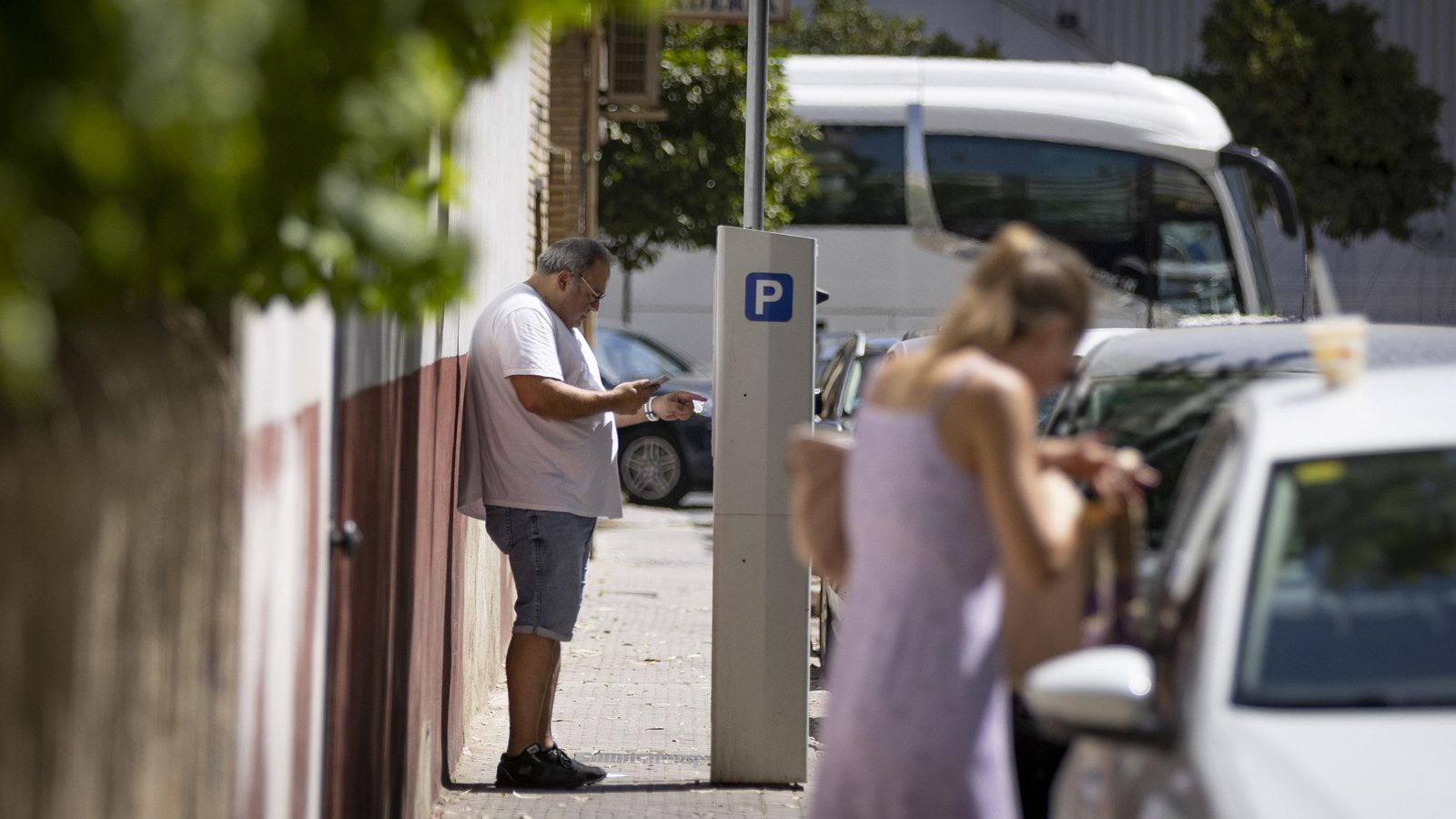 Un hombre paga el aparcamiento en un parquímetro.