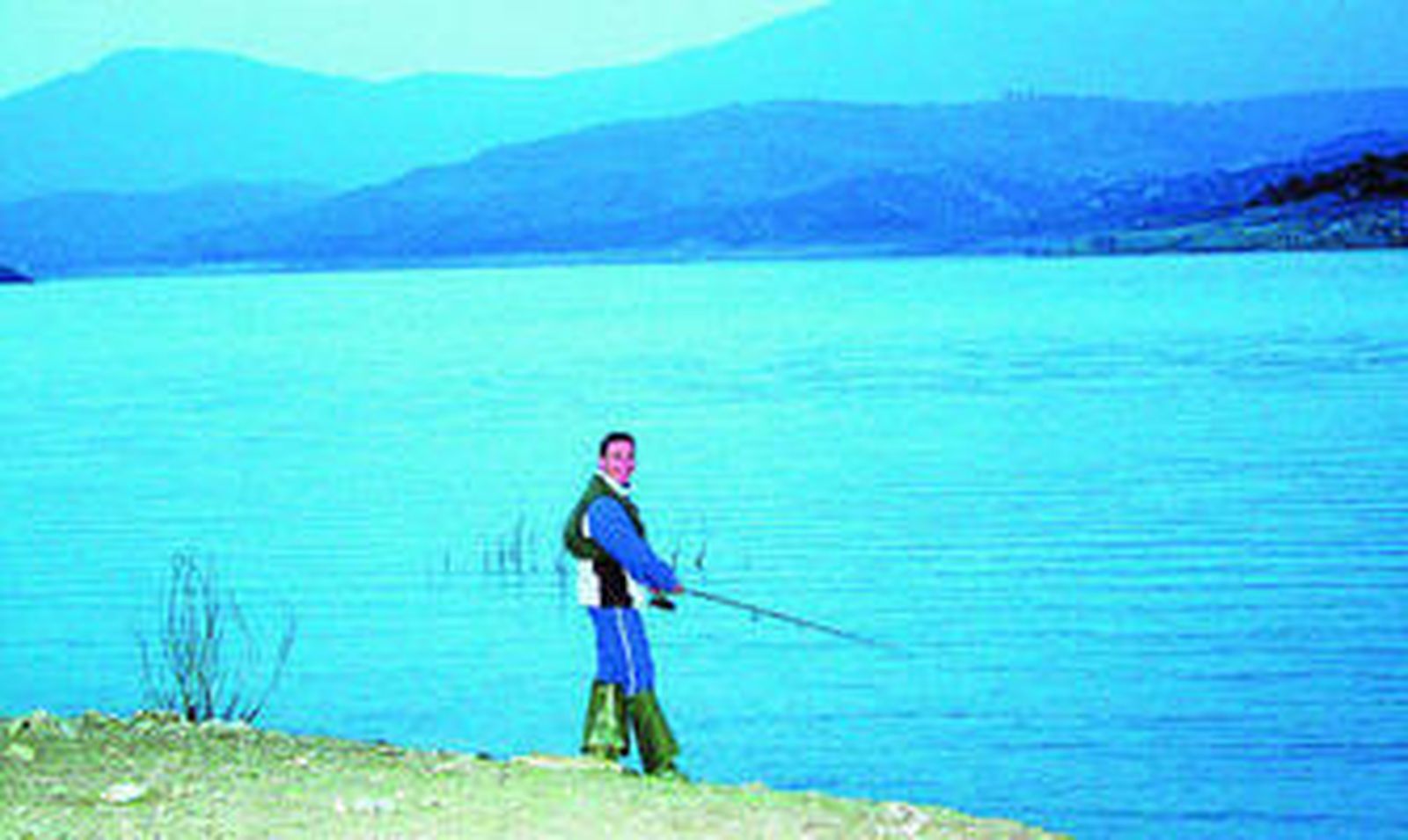 Un hombre pescando en el pantano de Zahara de la Sierra.