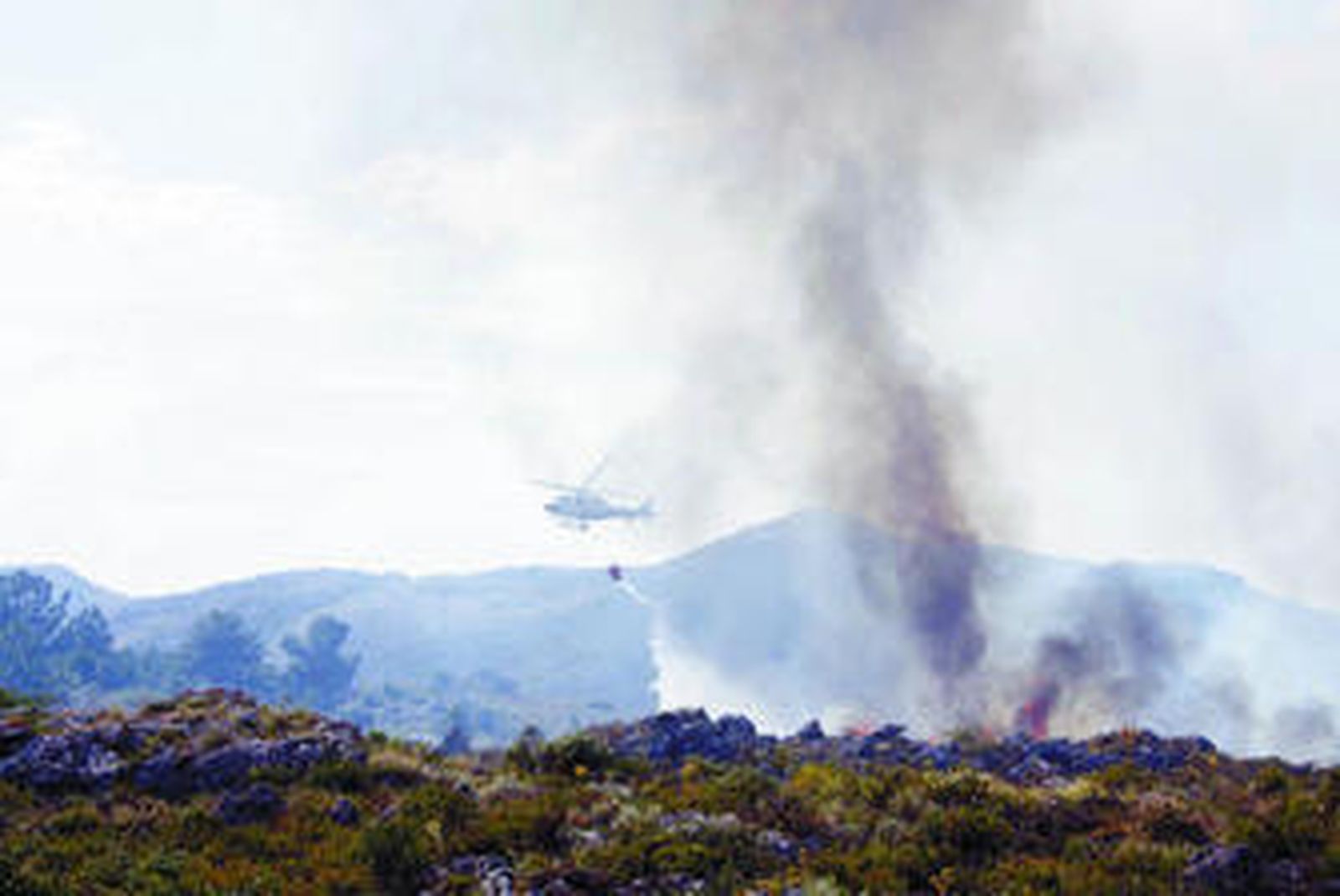 Un helicóptero descarga agua en el incendio de Parauta.