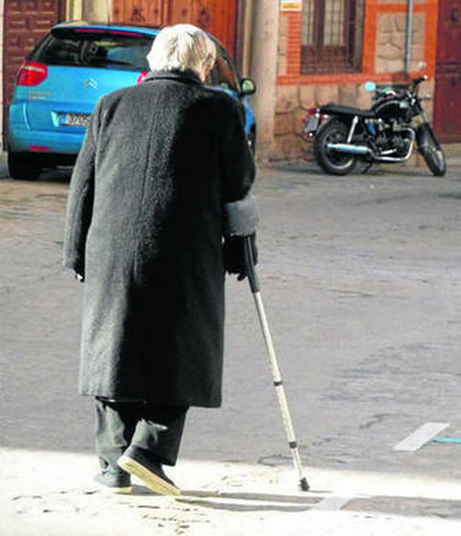 Una persona de avanza edad camina por la calle.
