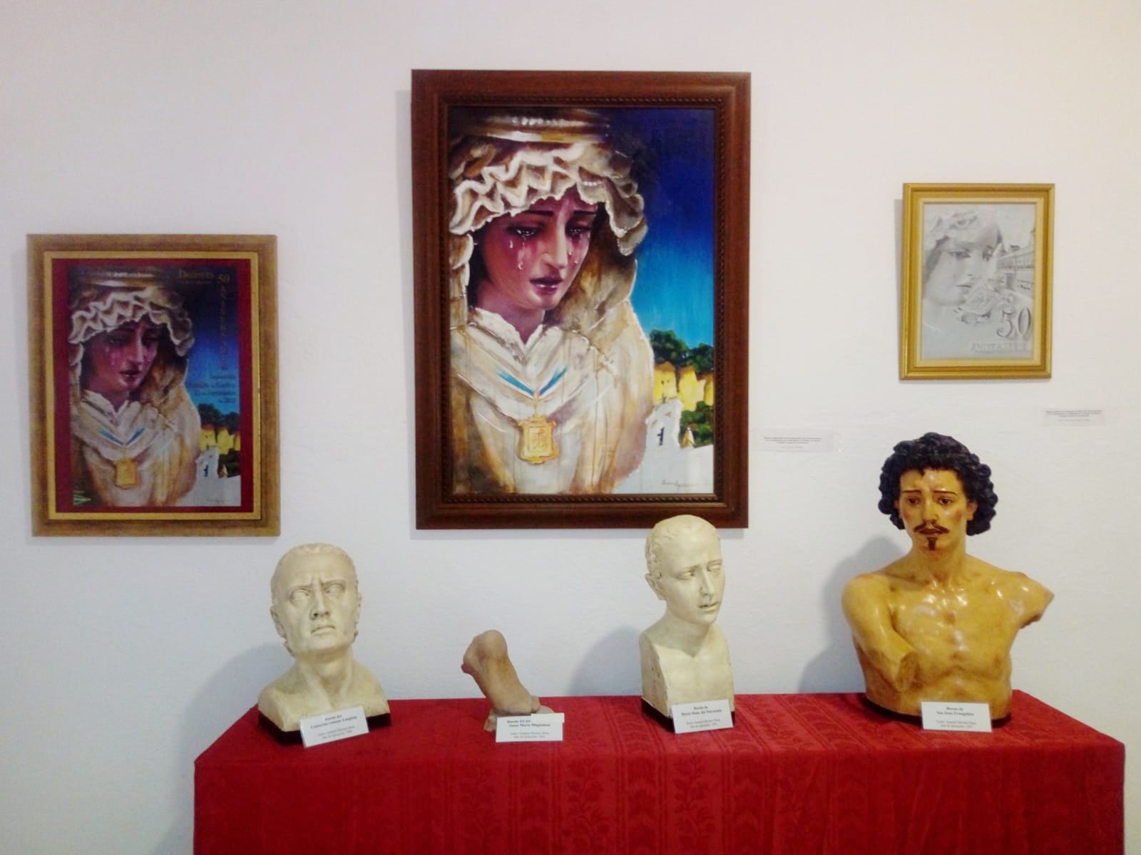 El cartel conmemorativo del cincuentenario, junto con varios bustos propiedad de la cofradía.