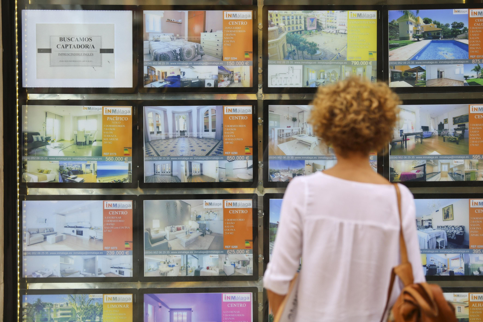 Una mujer observa el escaparate de una inmobiliaria en Málaga.
