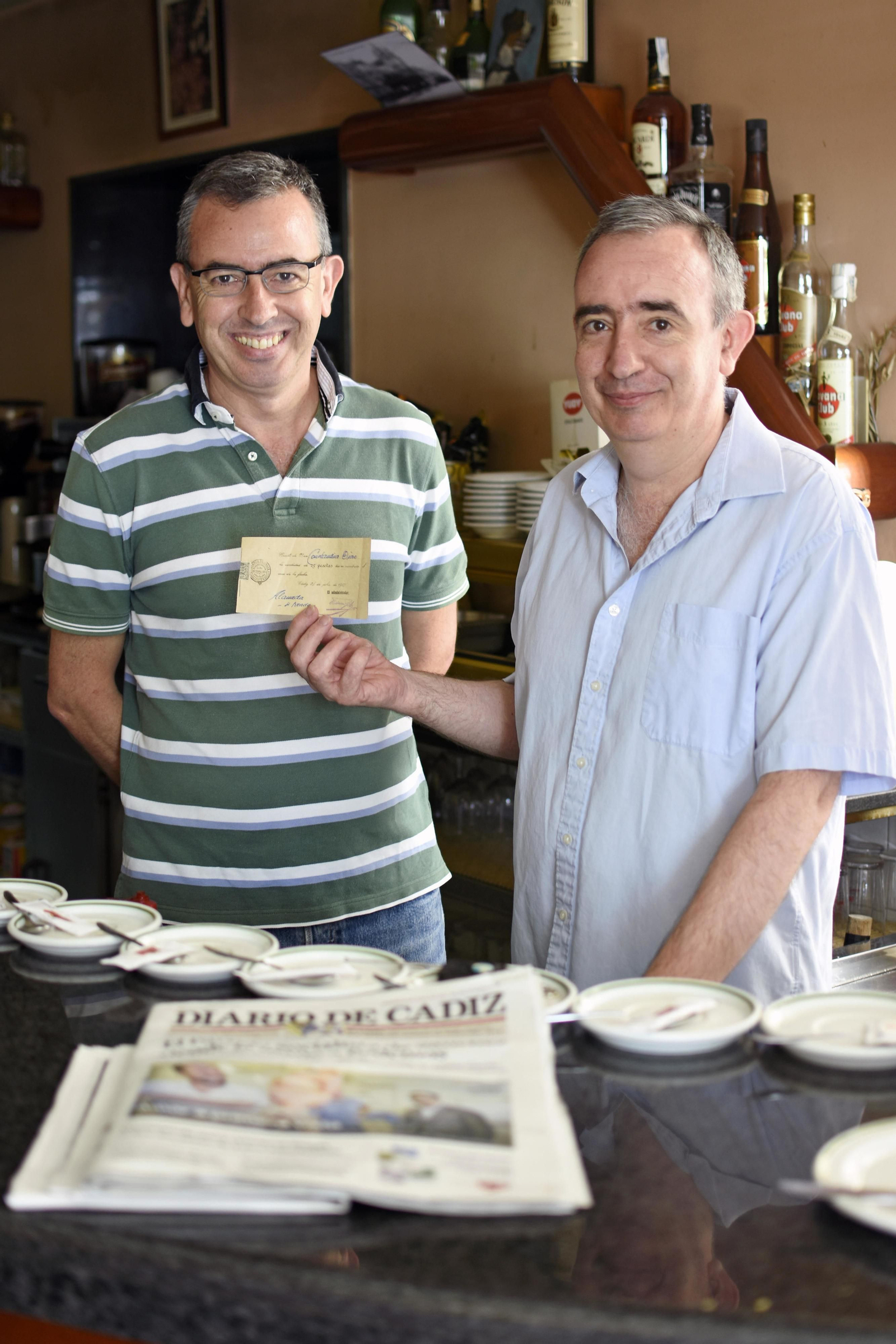 Julio y Tino ante su ejemplar diario y un recibo antiguo de suscripción.