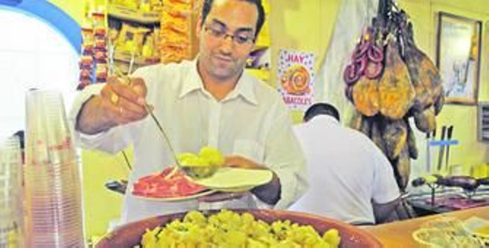 Uno de los camareros de la Casa de Extremadura sirve una tapa de papas aliñadas a uno de sus clientes.