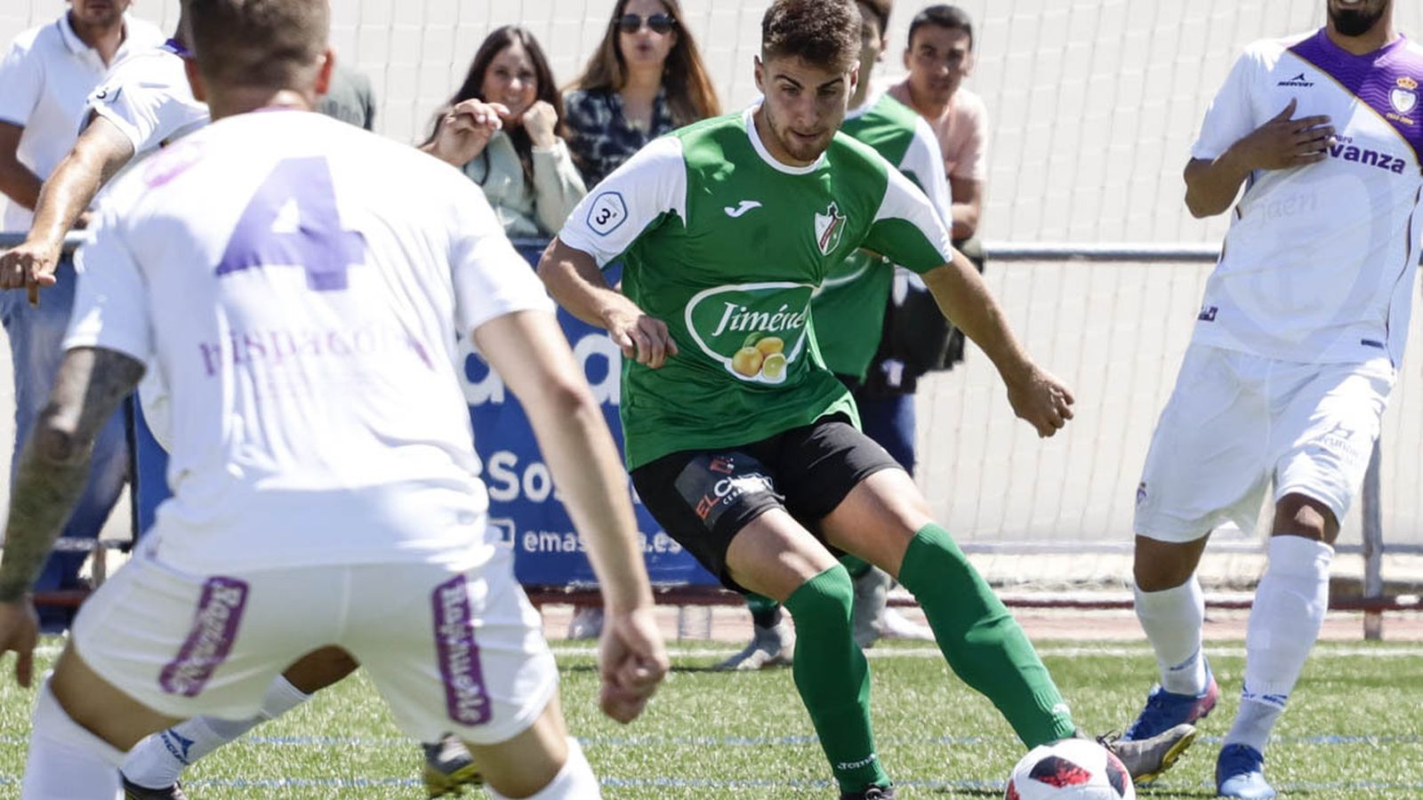 Un jugador del Huétor Vega es presionado por dos jienenses.