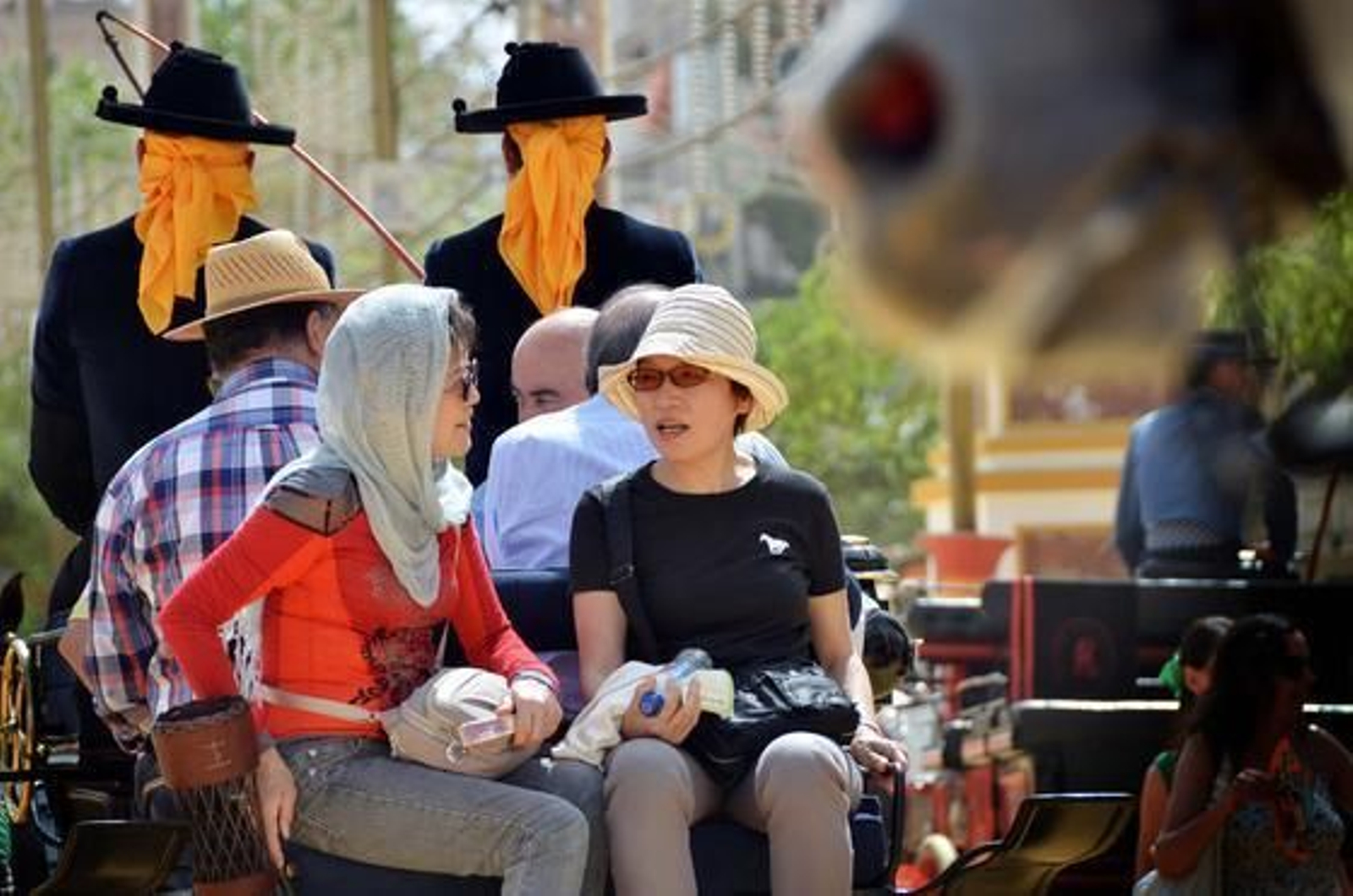 Inolvidable. Unos turistas se defienden del calor durante el paseo en coche de caballos, ayer, por el Real.   Foto: Manuel Aranda