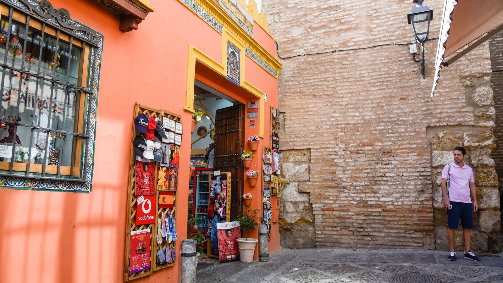 Gorras, azulejos y cucharas, entre otros artículos, colgados en la entrada de un establecimiento que linda con la muralla del Real Alcázar.