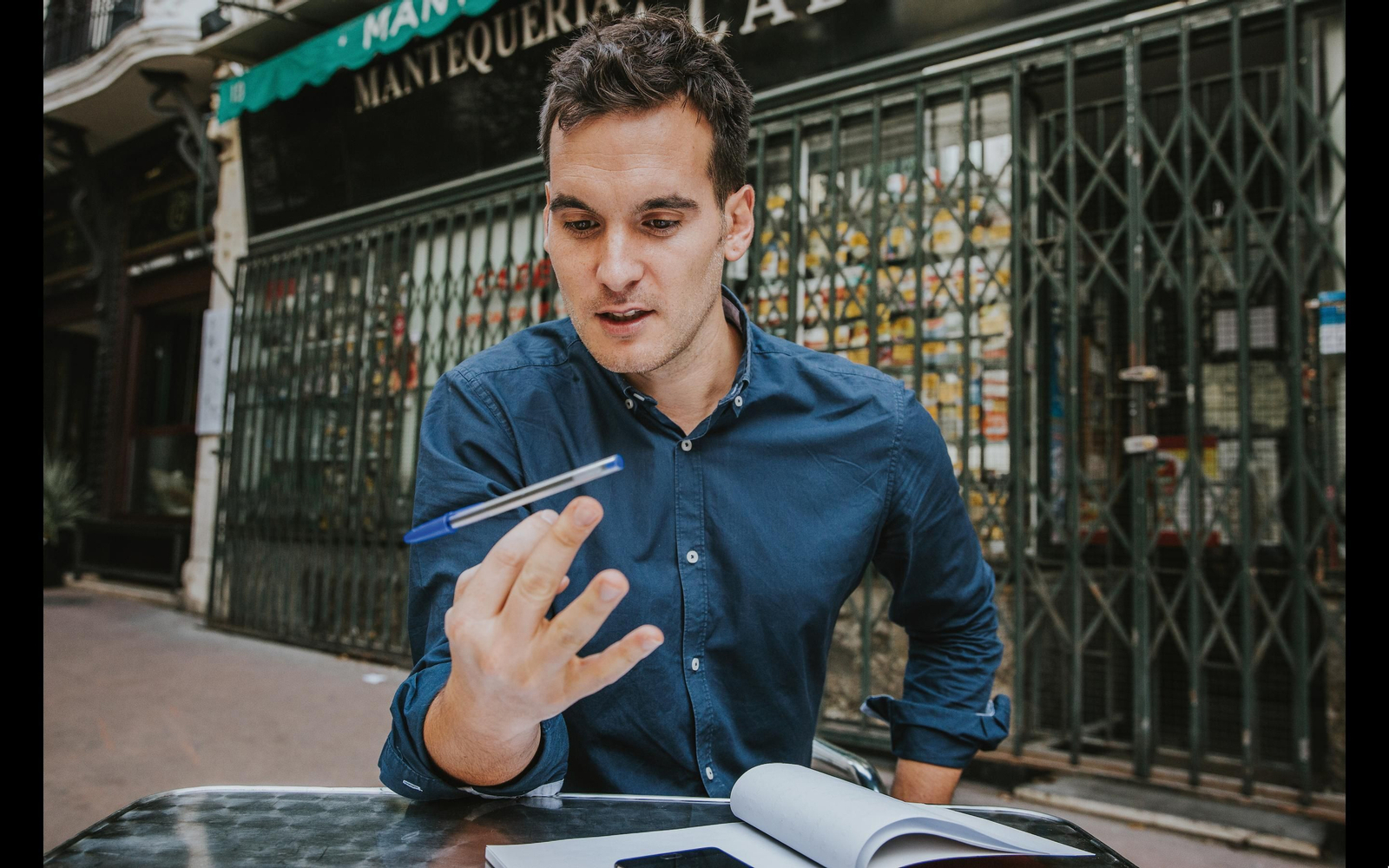 Julio Muñoz juega con un bolígrafo delante de la histórica Mantequería Bellido, en Madrid.
