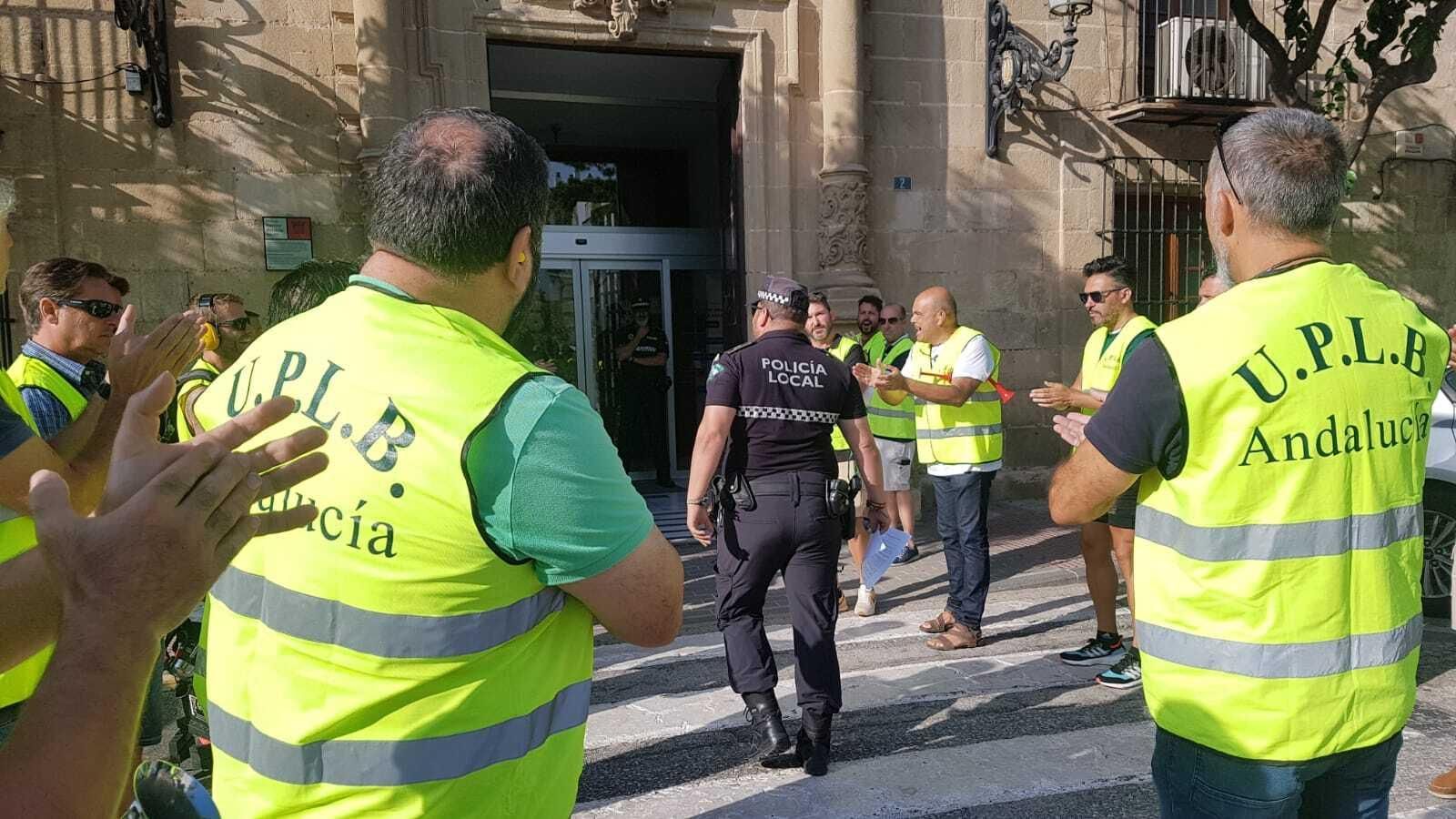 Uno de los agentes, entrando en el edificio municipal arropado por sus compañeros para la toma de declaración.