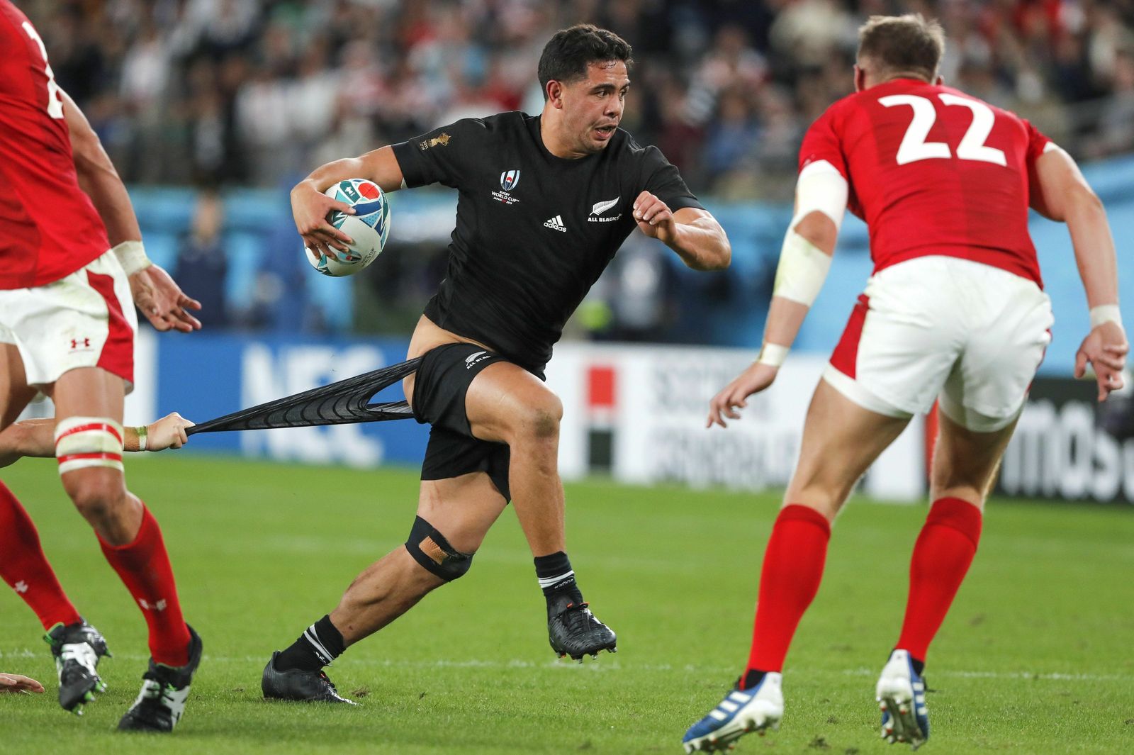 El neozelandés  Lienert-Brown es agarrado del calzón ante el galés Dan Biggar.