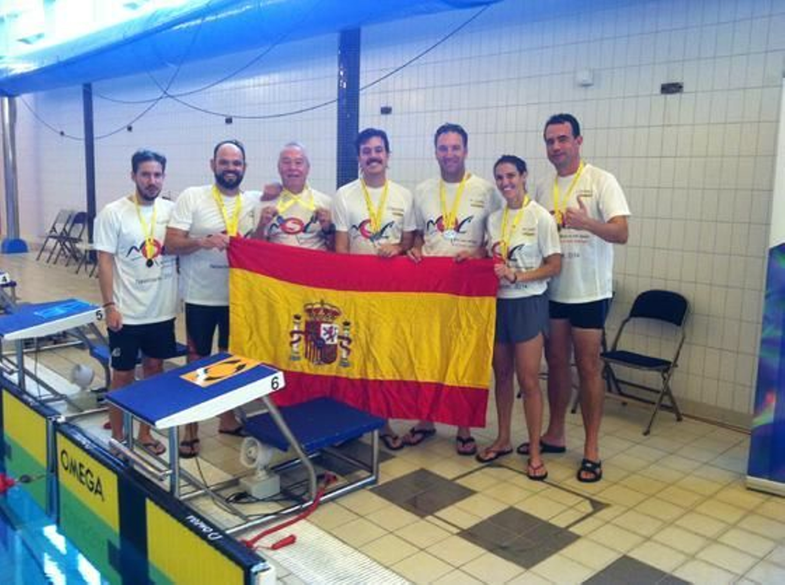 El grupo de nadadores posa junto a la bandera a la finalización de la competición