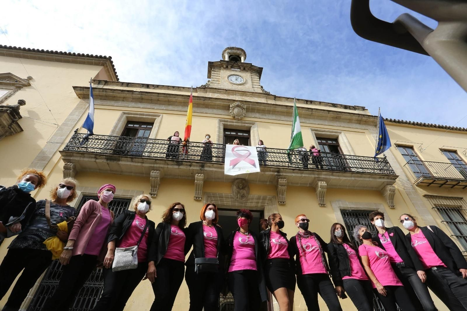 Mujeres de la asociación de mastectomizadas, bajo el balcón del Ayuntamiento con el lazo rosa.