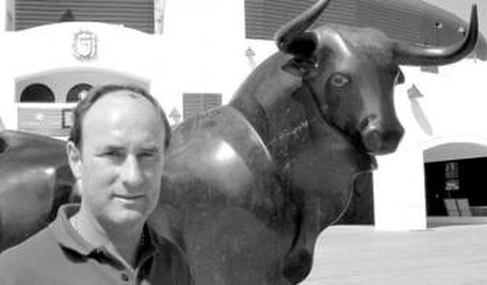 Fermín Vioque junto a la estatua del toro que guarda la puerta principal del coso de Roquetas.