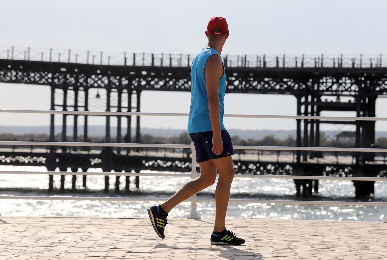 Un hombre practica deporte mientras observa el Muelle del Tinto al fondo.