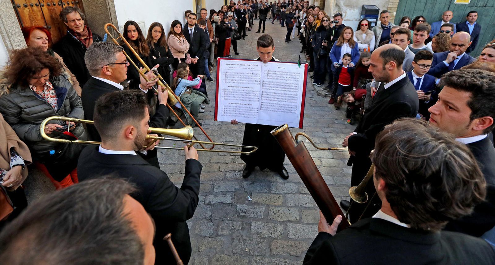 Un pequeño monaguillo sostiene el libro donde se leen las partituras de los ministriles que acompañan a la Vera Cruz.
