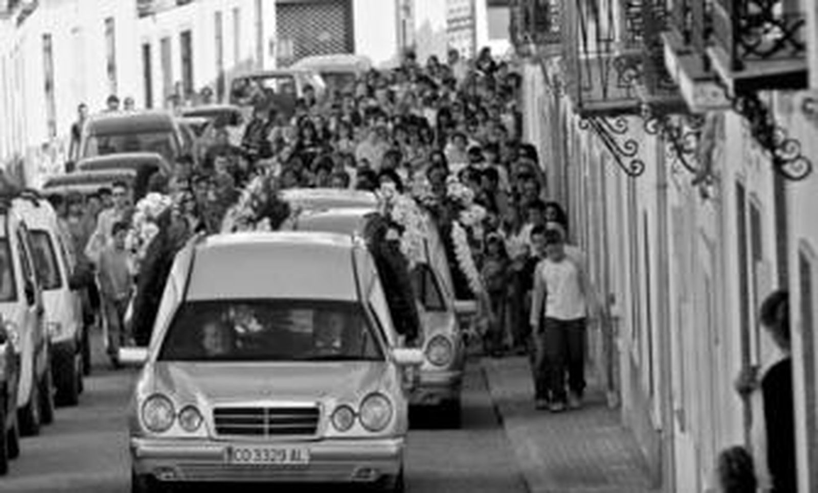 Los tres féretros marchan camino del cementerio de Villaviciosa con un mar de vecinos acompañándolos.