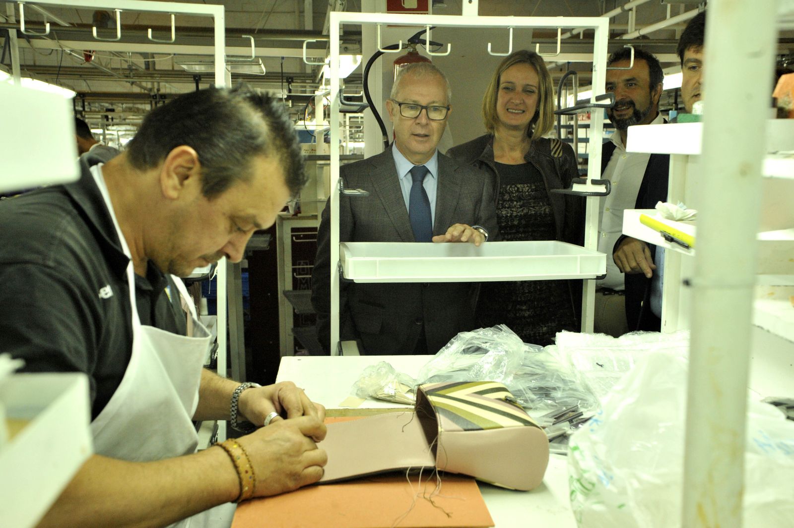Un operario confeccionando ayer un bolso en la firma Dimopel, bajo la mirada del delegado del Gobierno andaluz en Cádiz y la alcaldesa  de Ubrique.