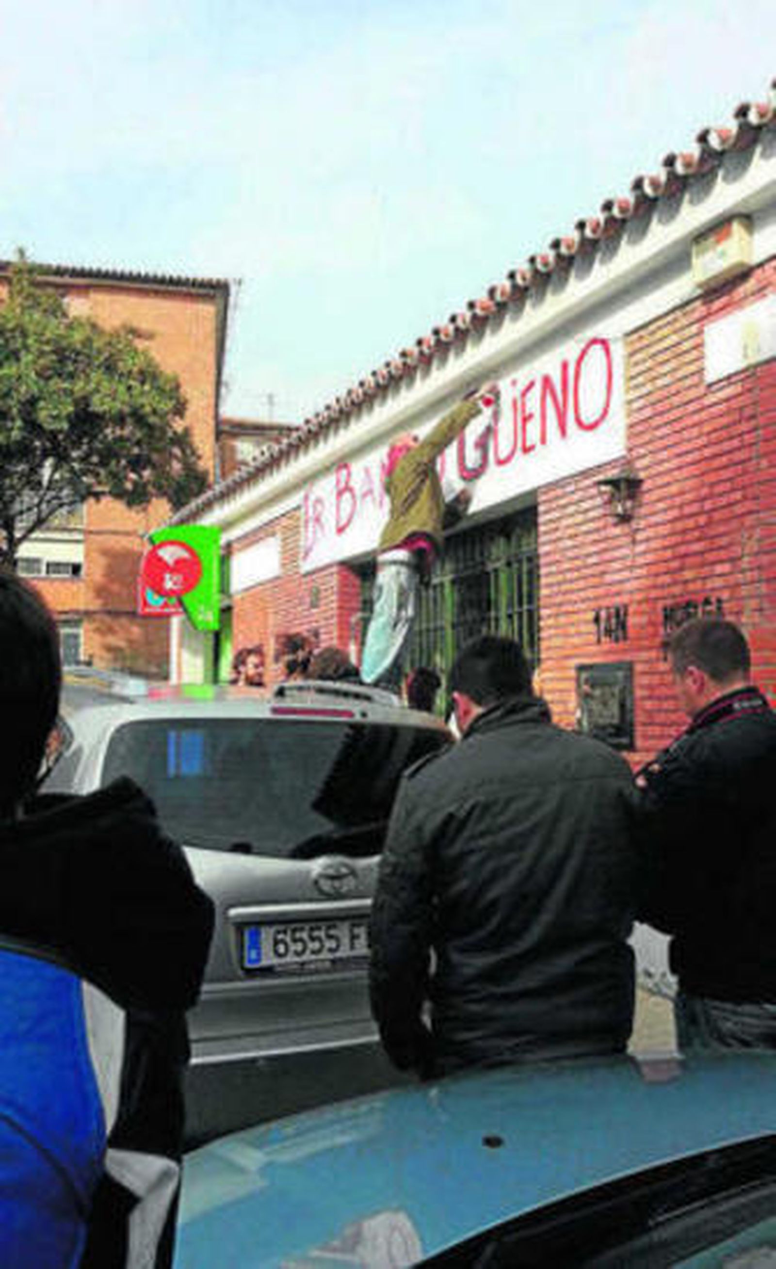 Los vecinos instalando, ayer, el cartel de 'Er banco güeno'.