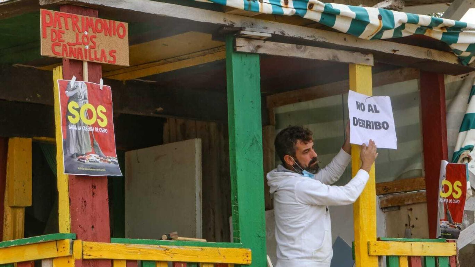 Carteles contra el derribo de las casetas en La Casería.