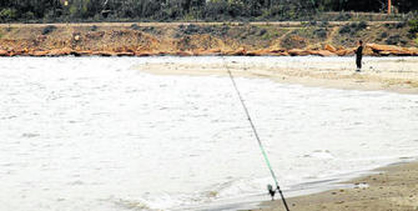Un hombre pesca junto a la desembocadura del río Guadarranque, ayer por la mañana.