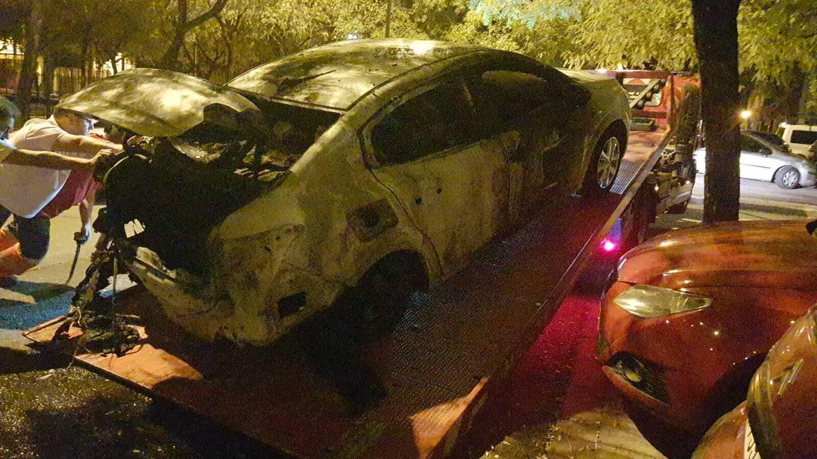 EL taxi calcinado es retirado de la vía pública por una grúa.