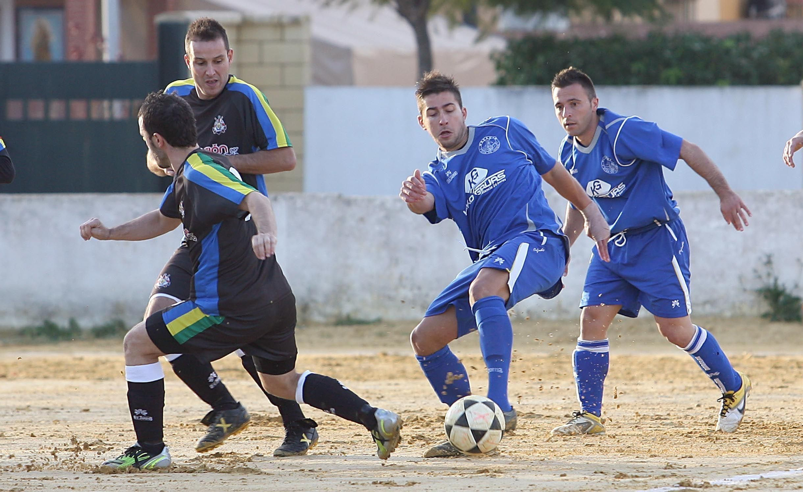 Jugadores del Punta Umbría y del Mazagón luchan por una pelota en el barro.