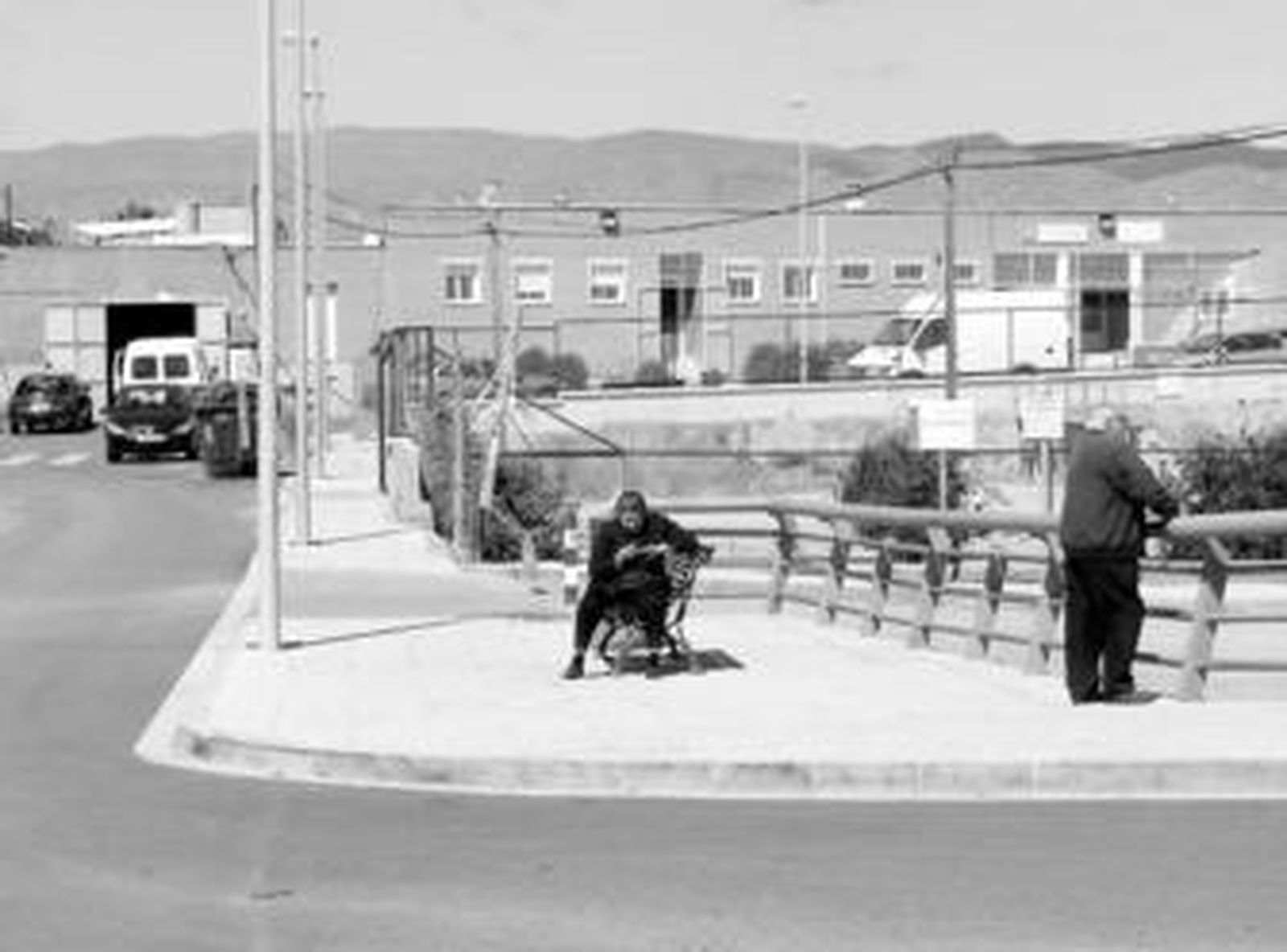 Dos vecinos esperan el autobús en la entrada a los accesos al ambulatorio.
