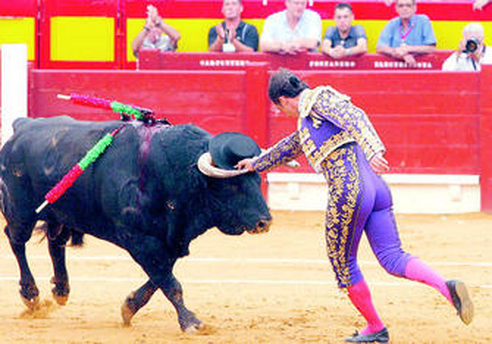 El Fandi, en un adorno, coloca un sombrero en el testuz a su primer toro, en el tercio de banderillas.