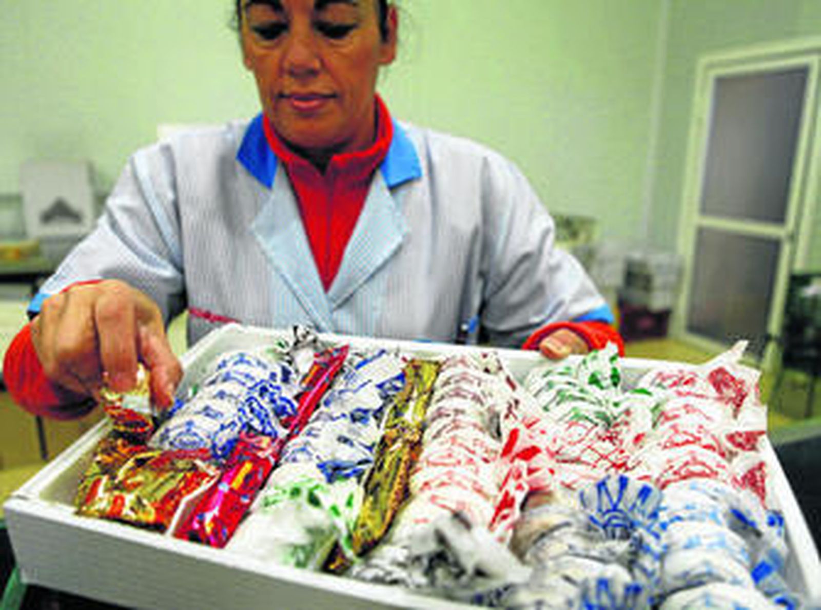 Una de las trabajadoras muestra una caja repleta de mantecados.