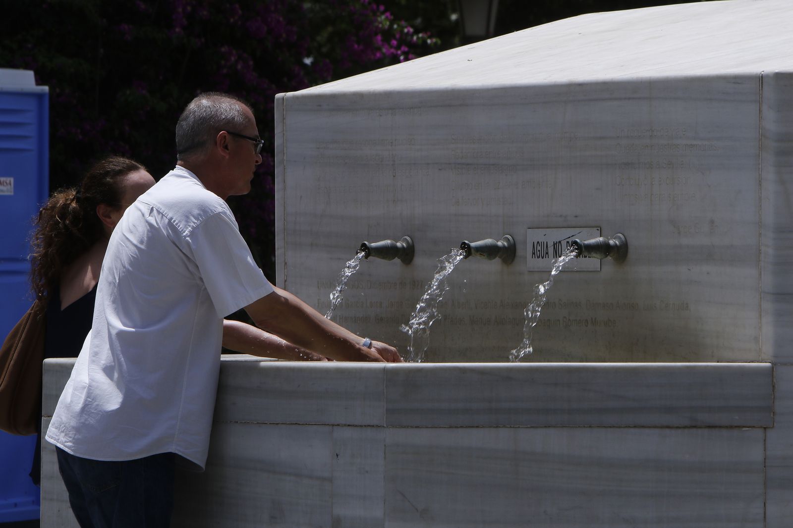 Un hombre se refresca en una fuente.