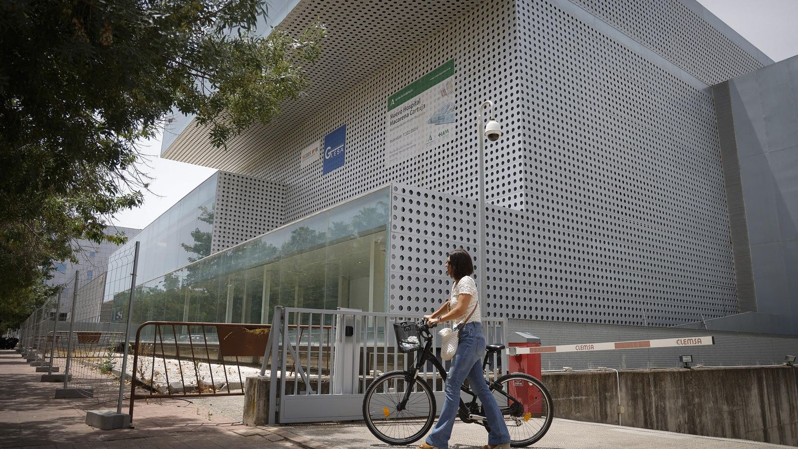 Una mujer pasa en bicicleta ante el edificio que acogerá el Hospital Macarena Cartuja.