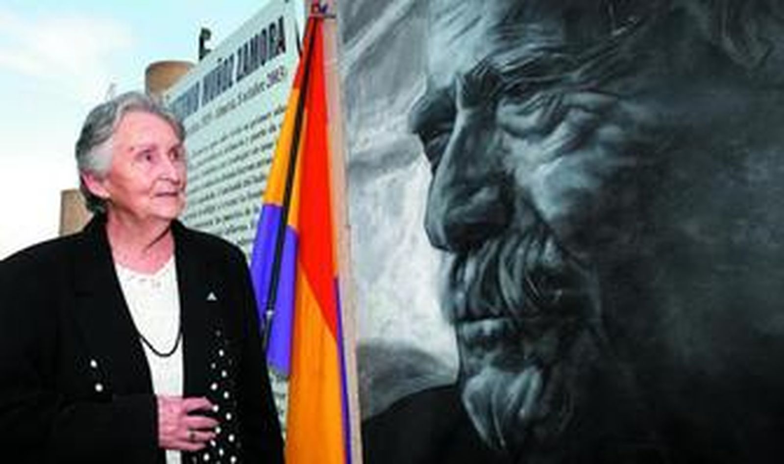 La viuda de Antonio Muñoz Zamora junto al retrato de su marido realizado con arena de Níjar por Arnaud Berliaz.