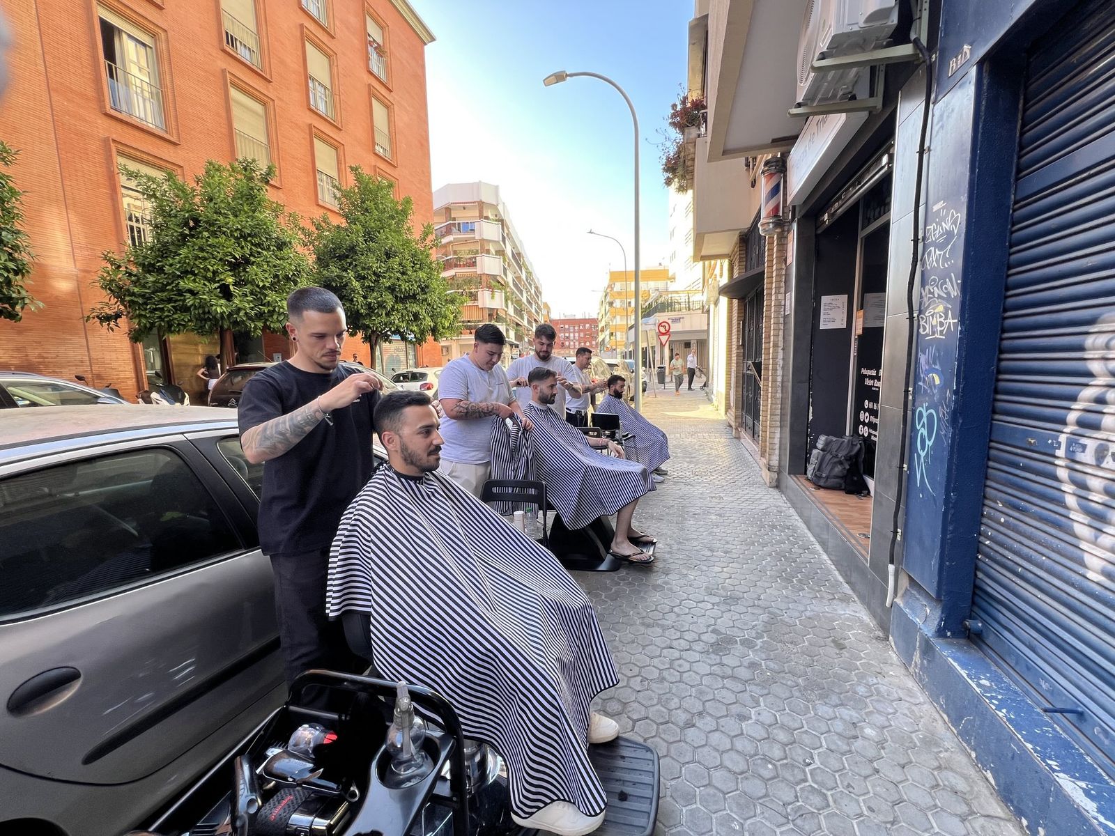 Barberos de Triana pelando a sus clientes en la calle en pleno apagón.
