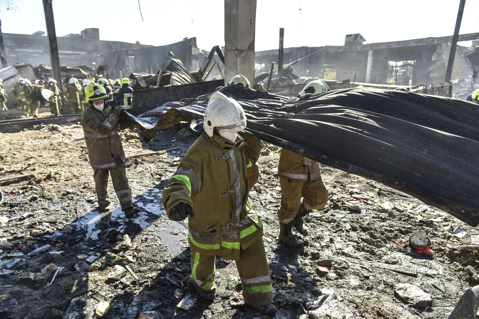 Bomberos retiran escombros del centro comercial atacado en Kremenchuk.