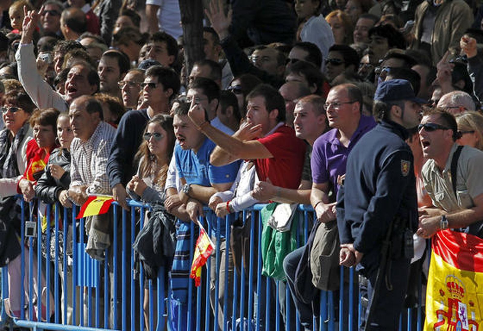 Algunos de los asistentes al desfile hacen gestos de mal gusto al presidente del Gobierno. / EFE