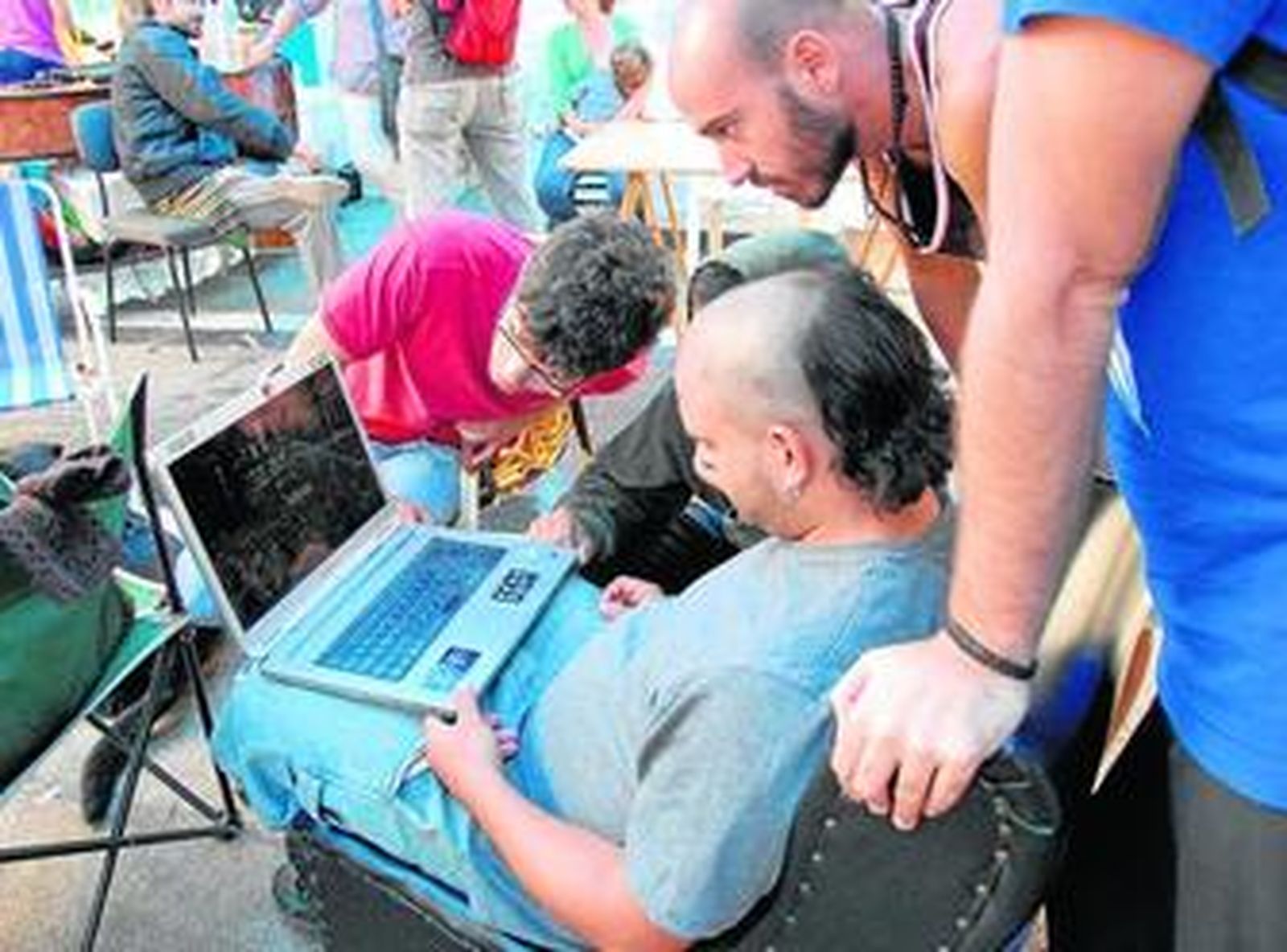 Jóvenes ayer en el campamento, mirando imágenes de la acampada de Sevilla a través de un portátil.