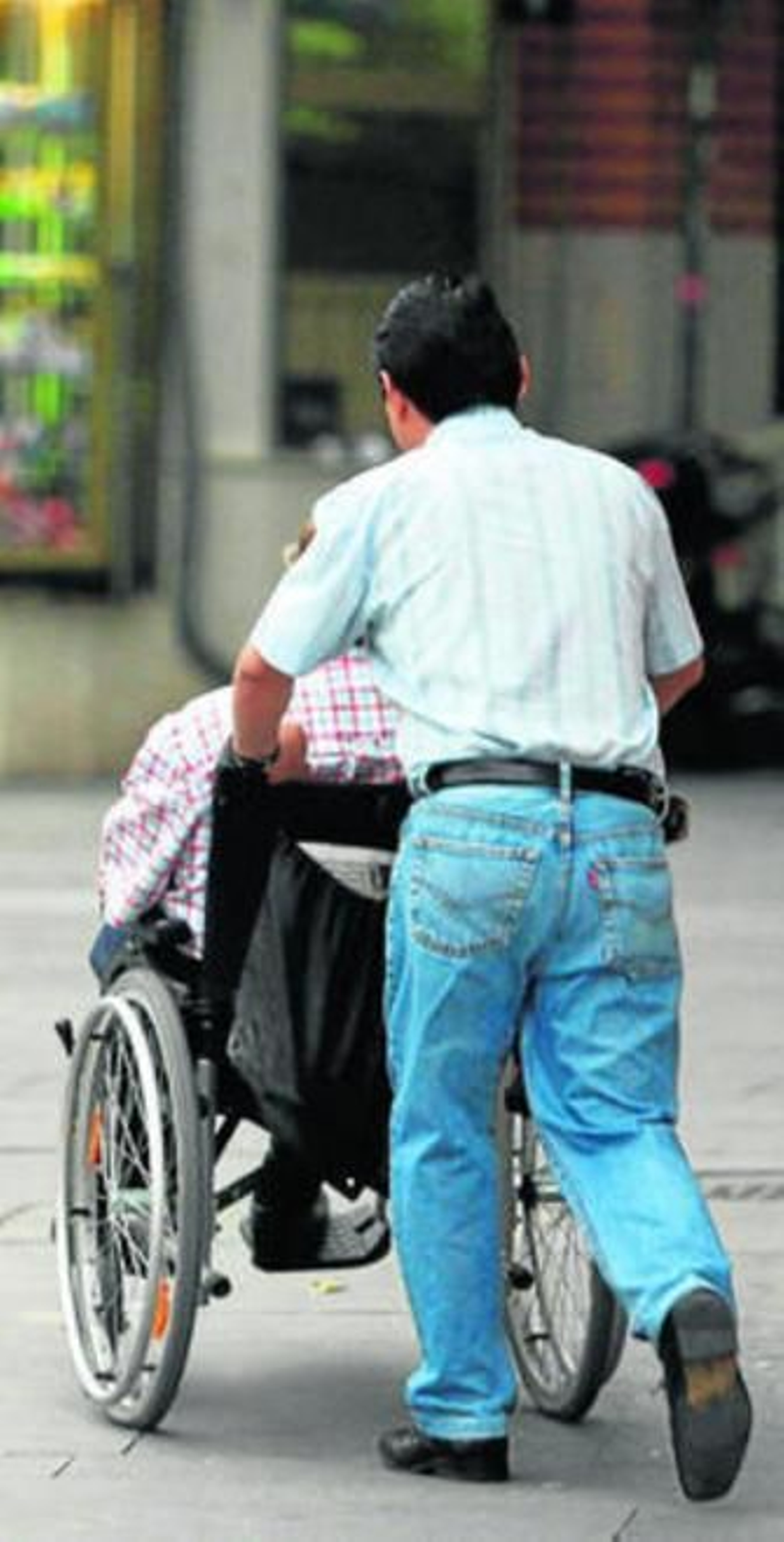 Un hombre pasea por la calle en silla de ruedas.