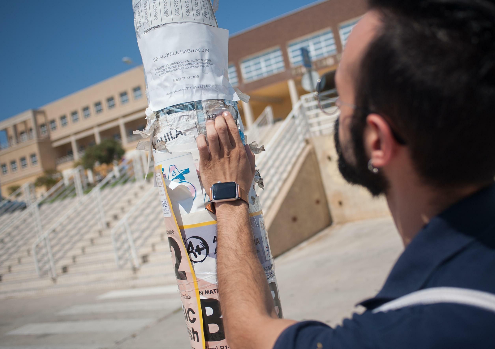 Un joven mirando un cartel en una farola.