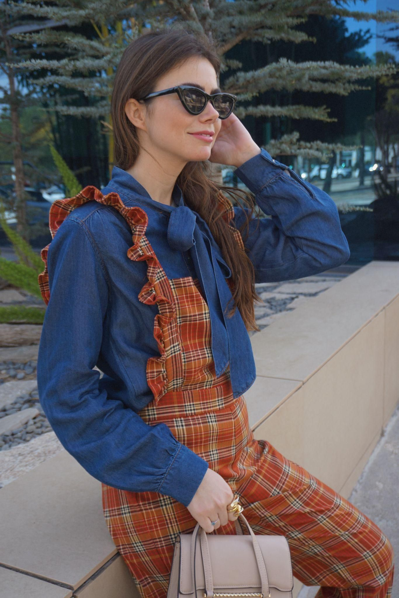 La influencer Carlota Huelva con una blusa con lazada y un peto de cuadros y volantes de El armario de Paola.