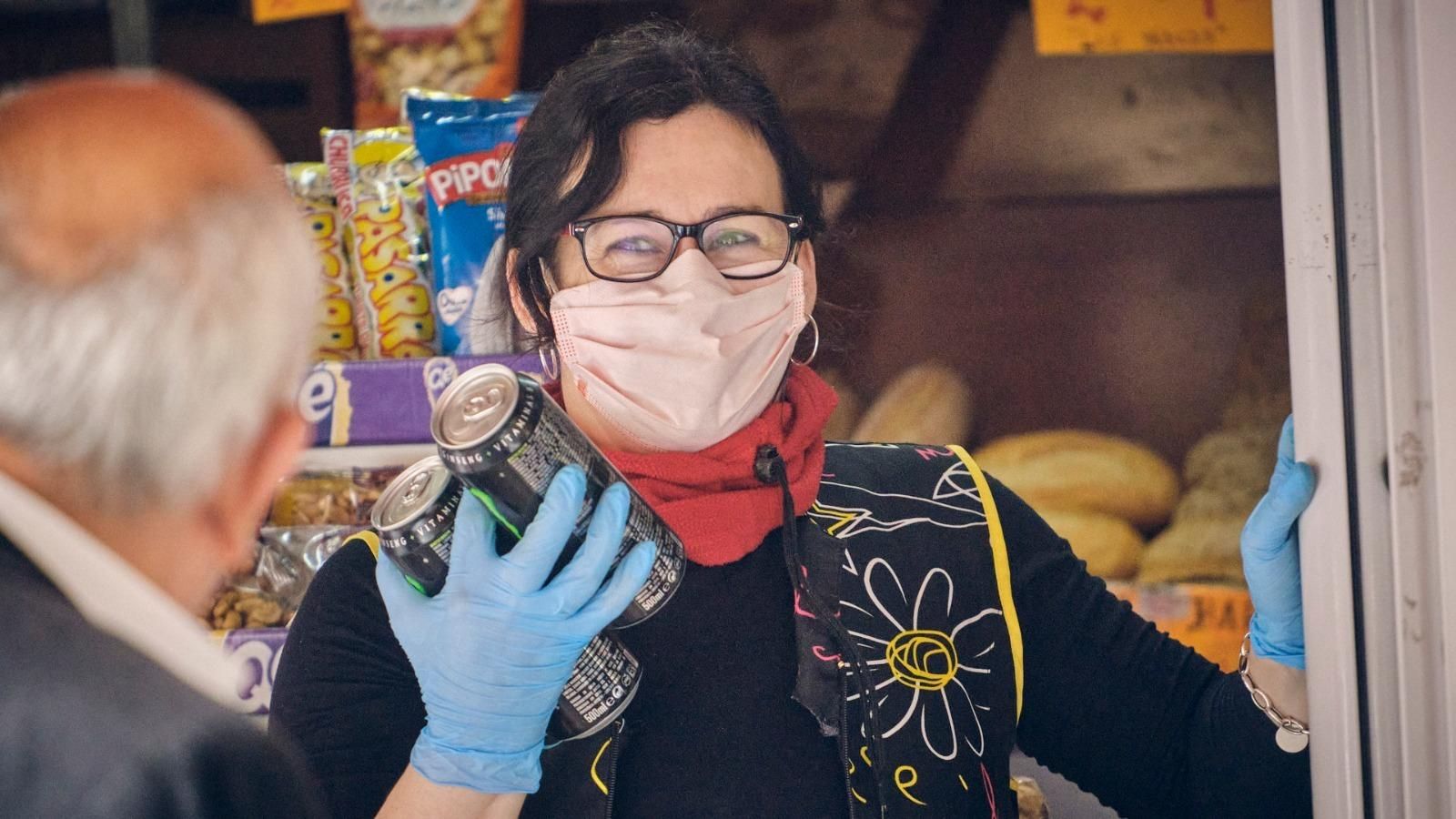 Una mujer con mascarilla atiende a un cliente en su establecimiento.